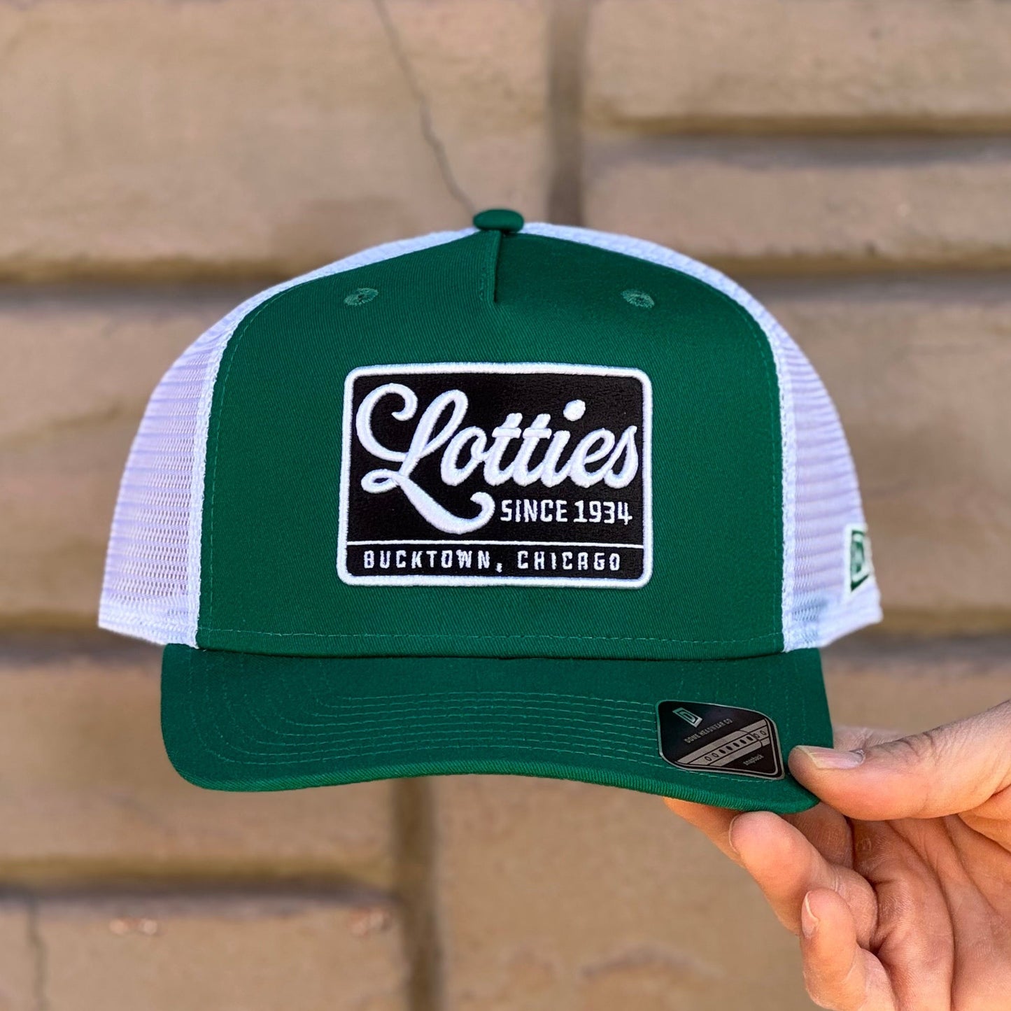 A green and white trucker hat with a black and white Lotties signature patch on the front.