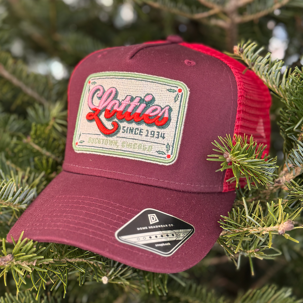 Maroon and red cap with a logo on a green leafy background